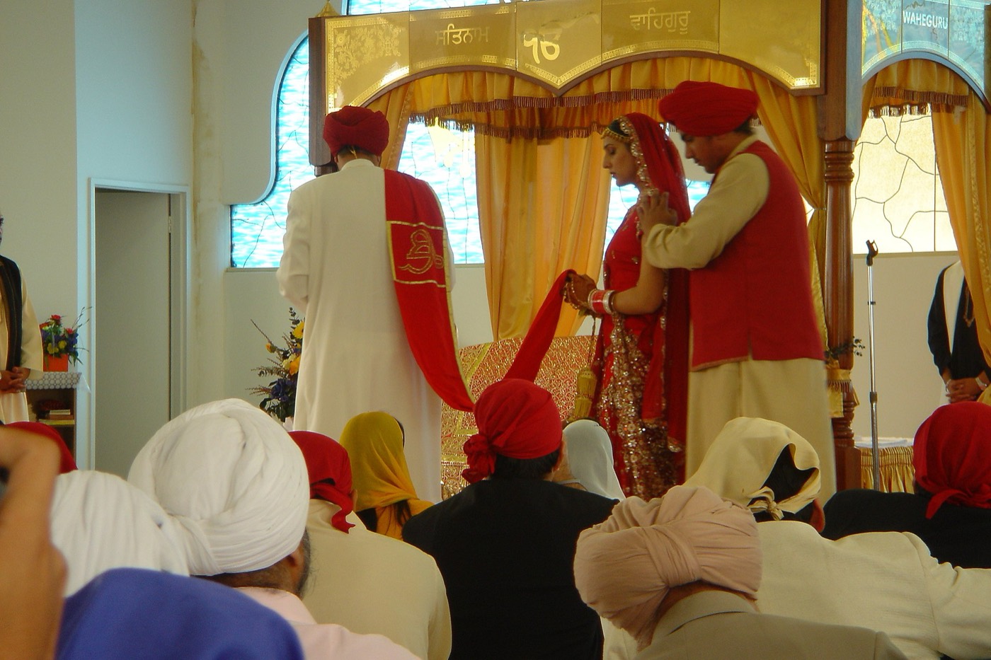 A Sikh bride and groom take the Lavaan, circling the Guru Granth Sahib Ji during their Anand Karaj wedding ceremony